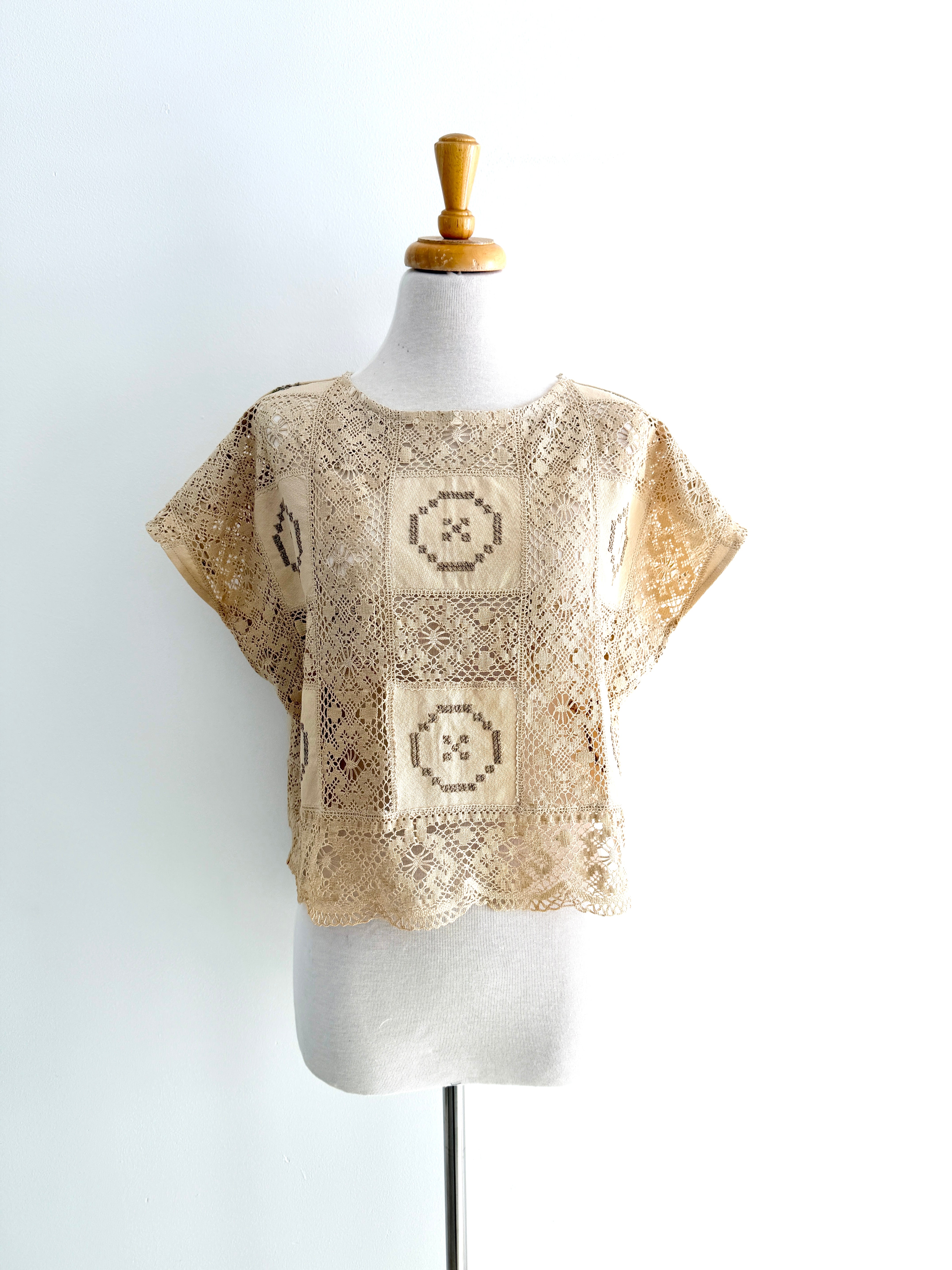Beige crochet top on a mannequin against a white background