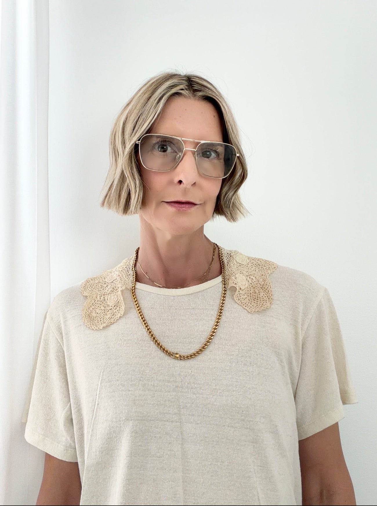 Woman wearing a light-colored top with lace details against a white background