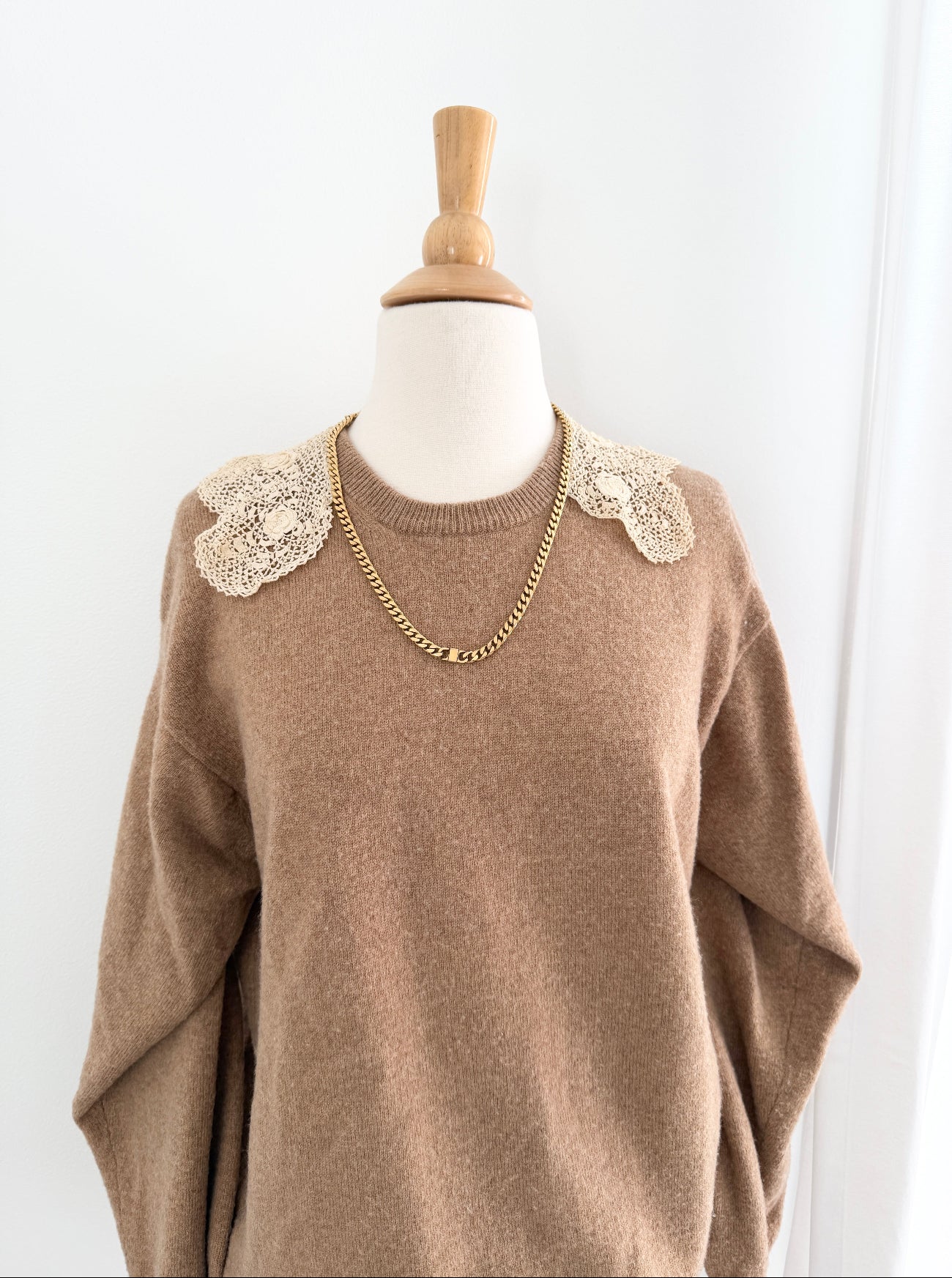 Brown sweater with floral embellishments on a mannequin against a white background