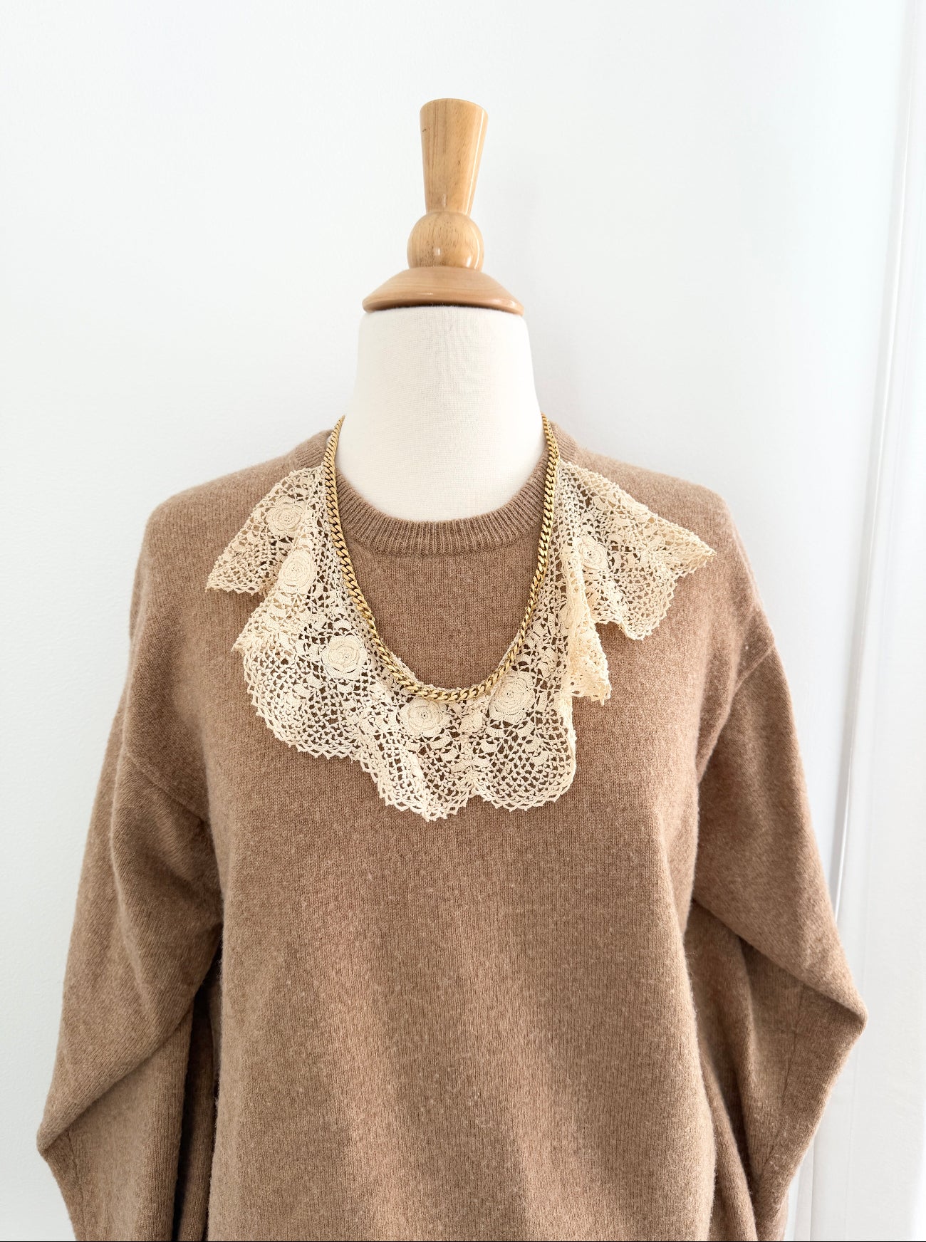 Brown sweater with lace collar on a mannequin against a white background