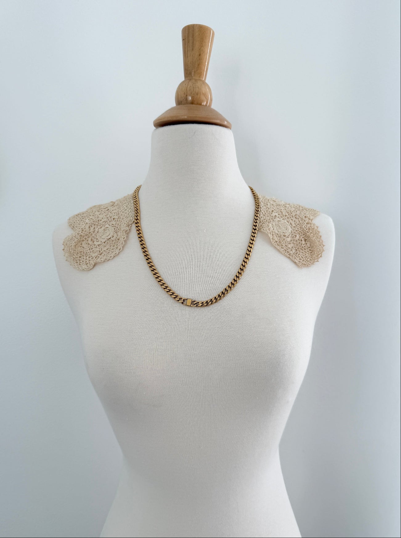 Mannequin wearing a necklace with decorative shoulder pieces on a plain background