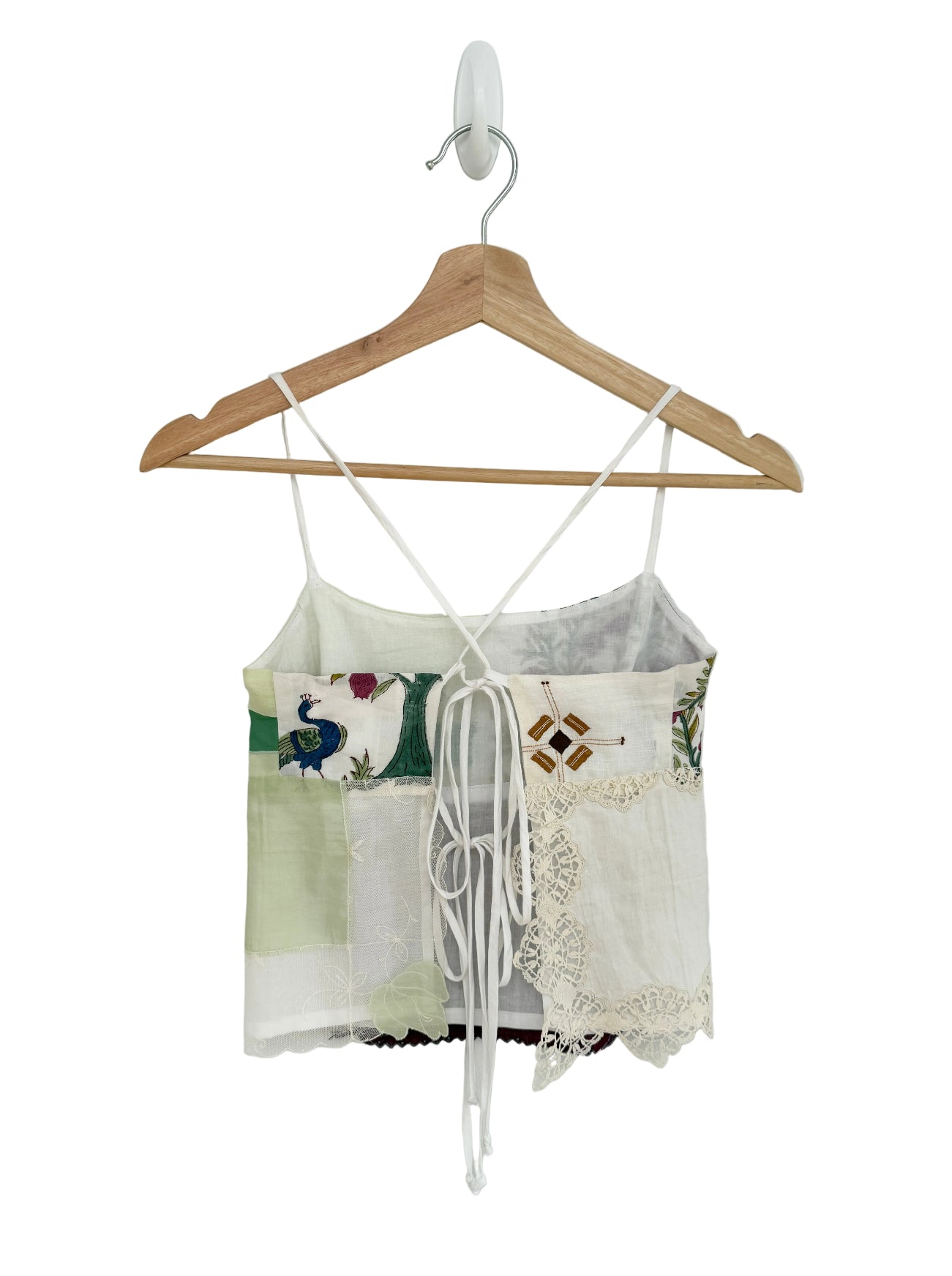 Vintage-style top with floral patterns and lace details on a wooden hanger against a white background