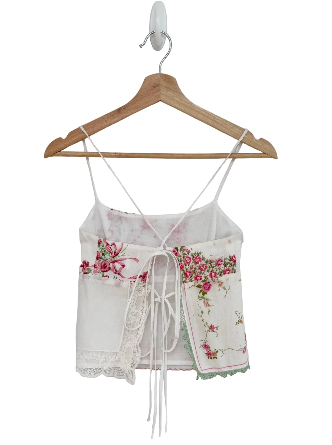 Floral top with lace details on a wooden hanger against a white background