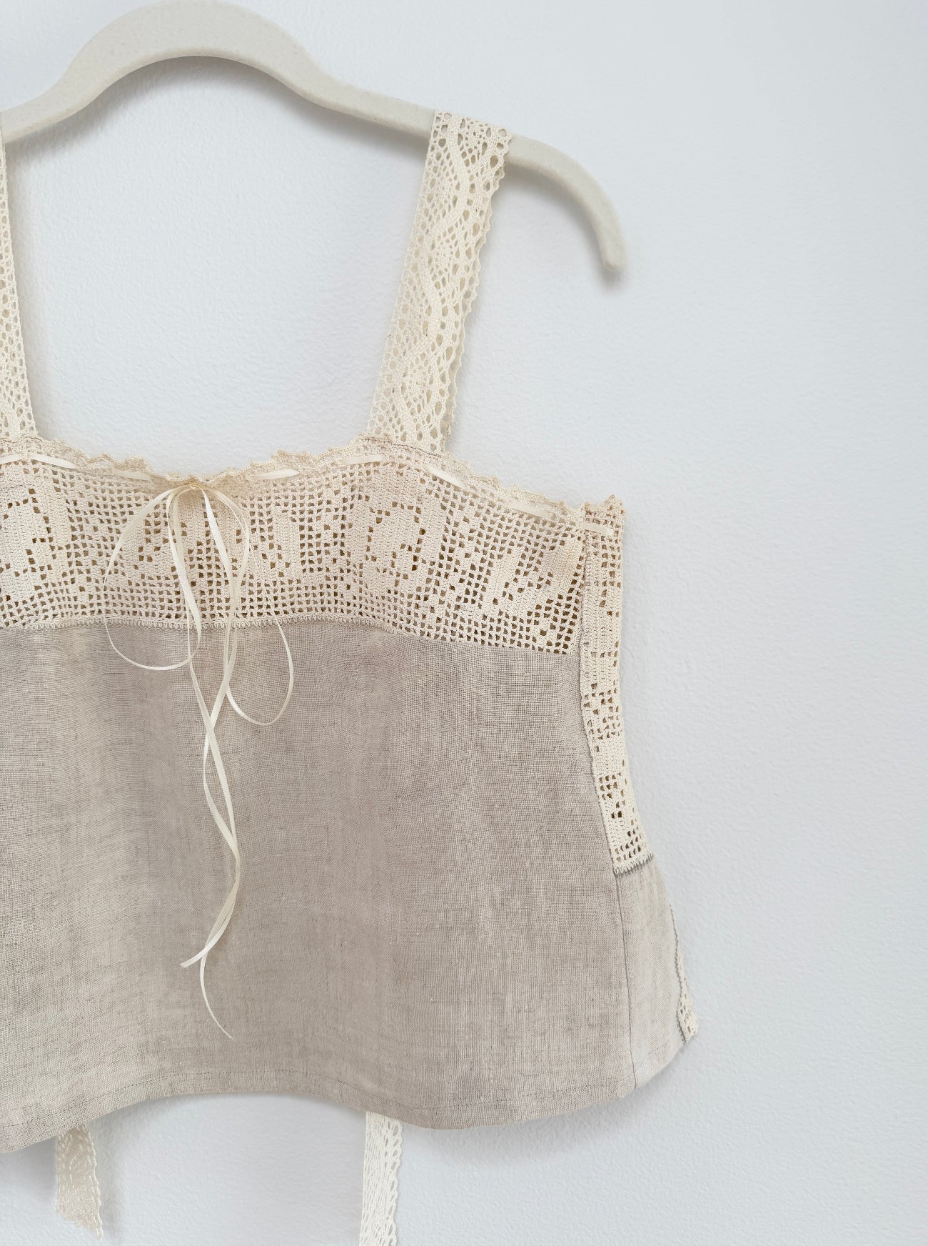 Light brown top with lace details on a white background