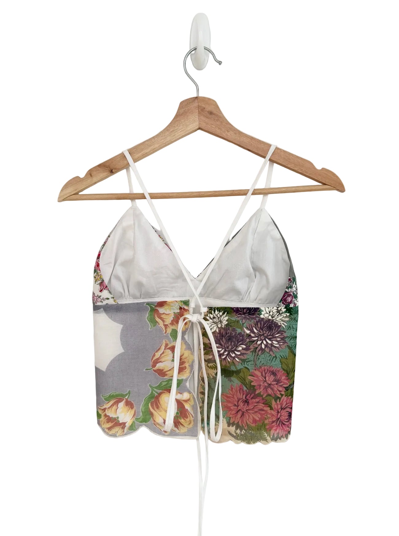 Floral-patterned top on a wooden hanger against a white background