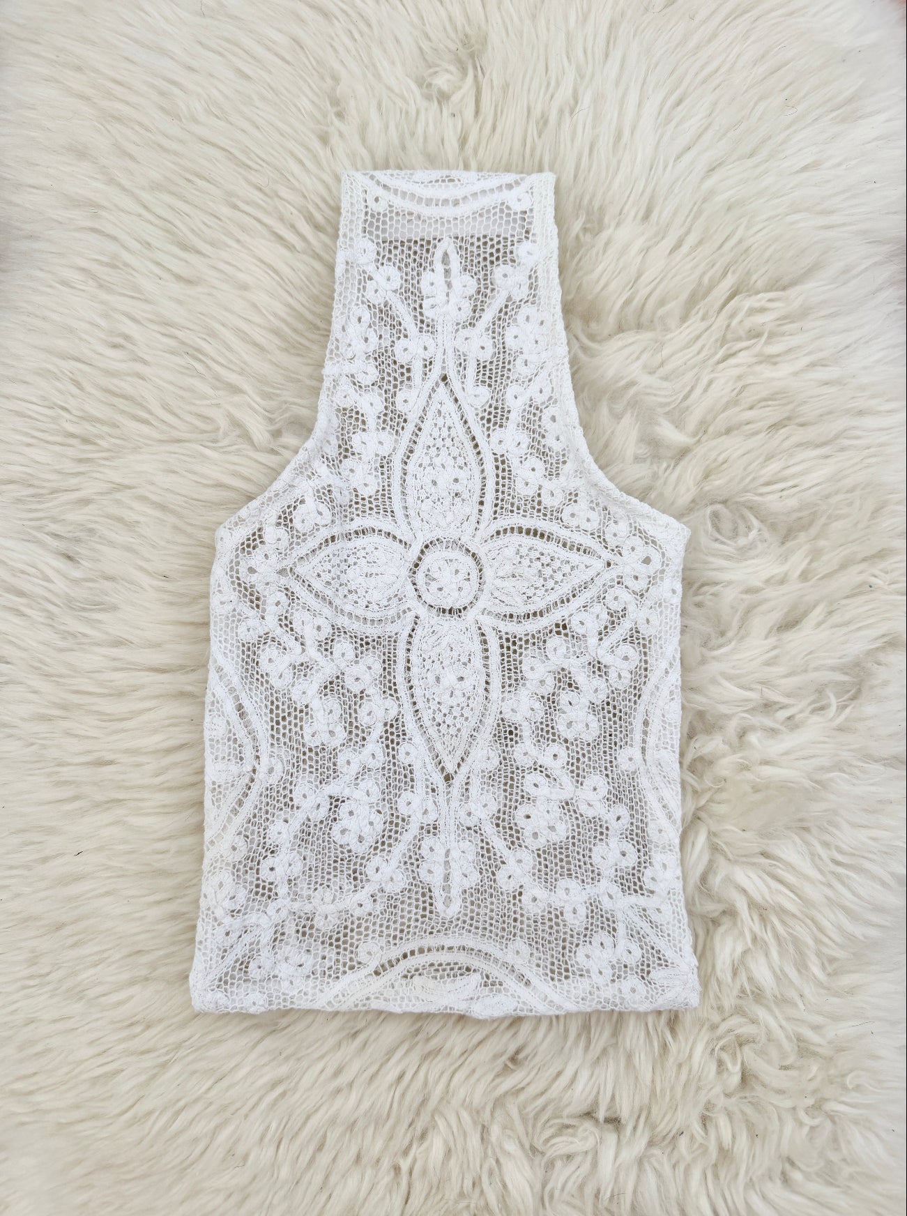 White lace mini handbag laid flat on a fluffy cream fur surface