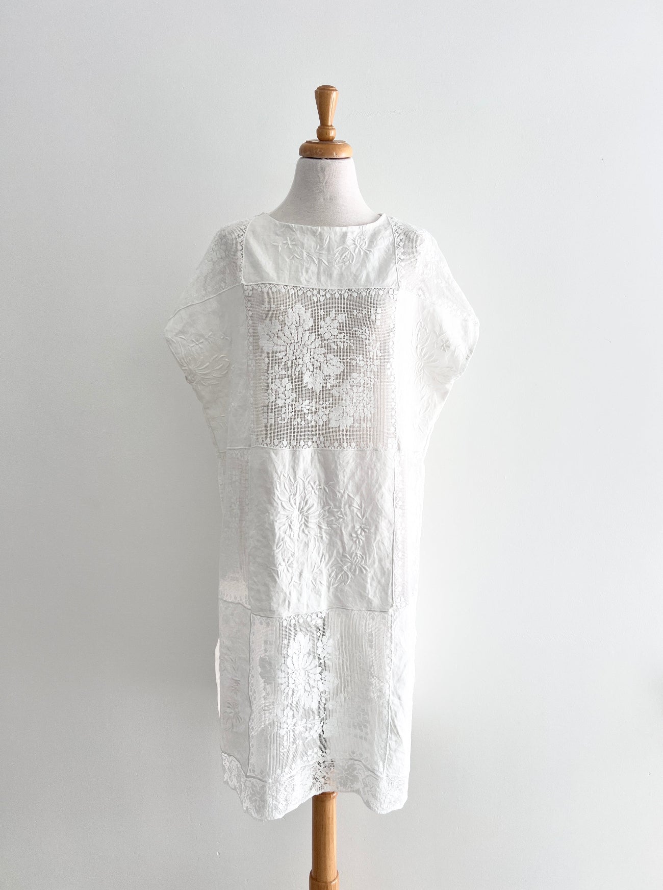 White embroidered dress on a mannequin against a plain background