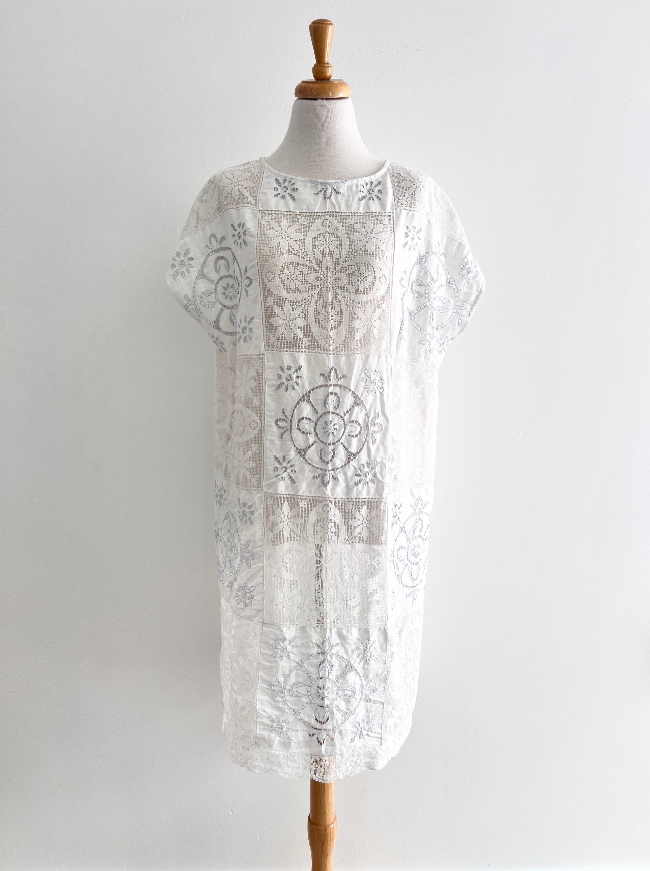White lace dress on a mannequin against a plain background