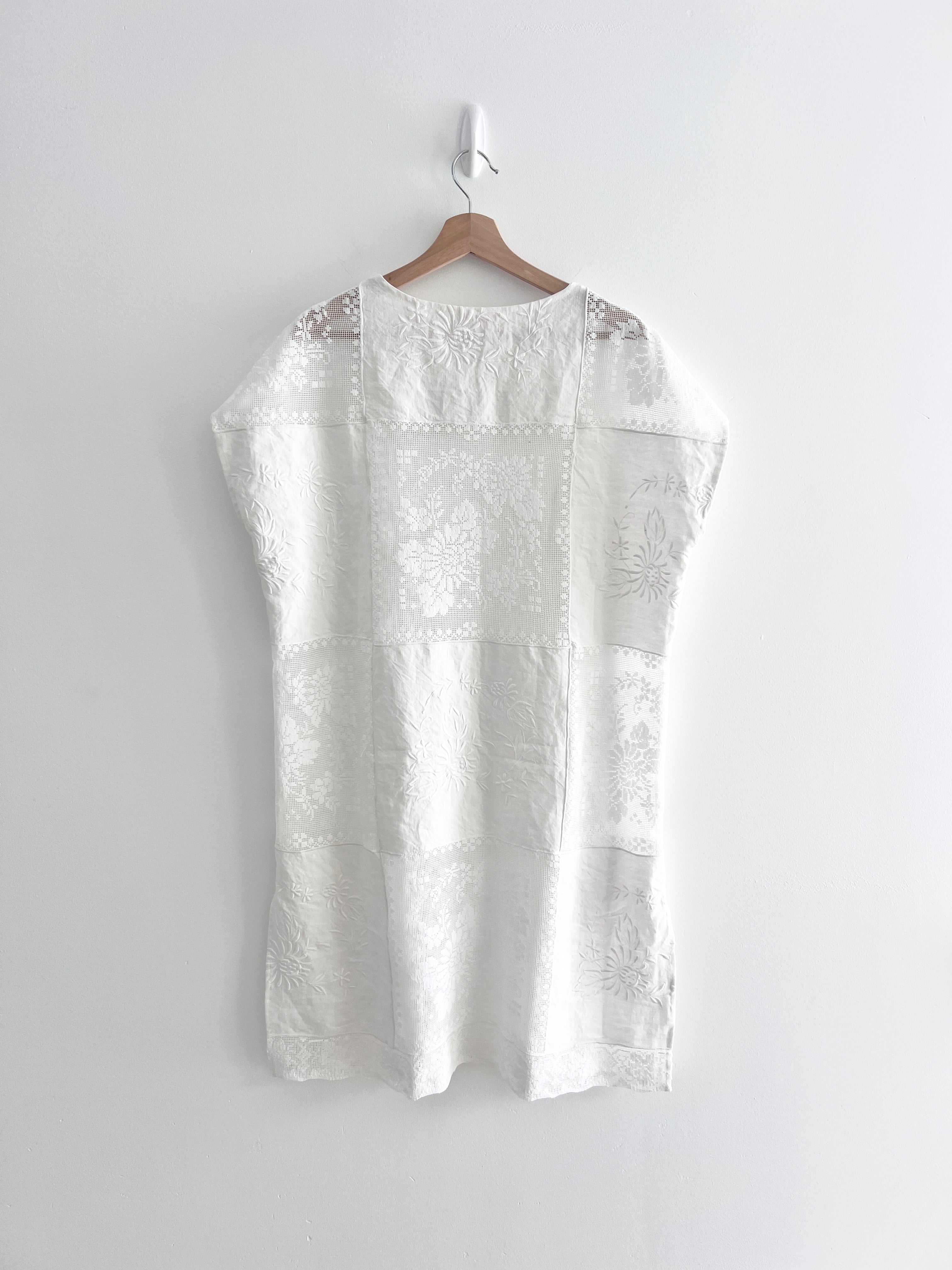 White embroidered dress on a hanger against a white background