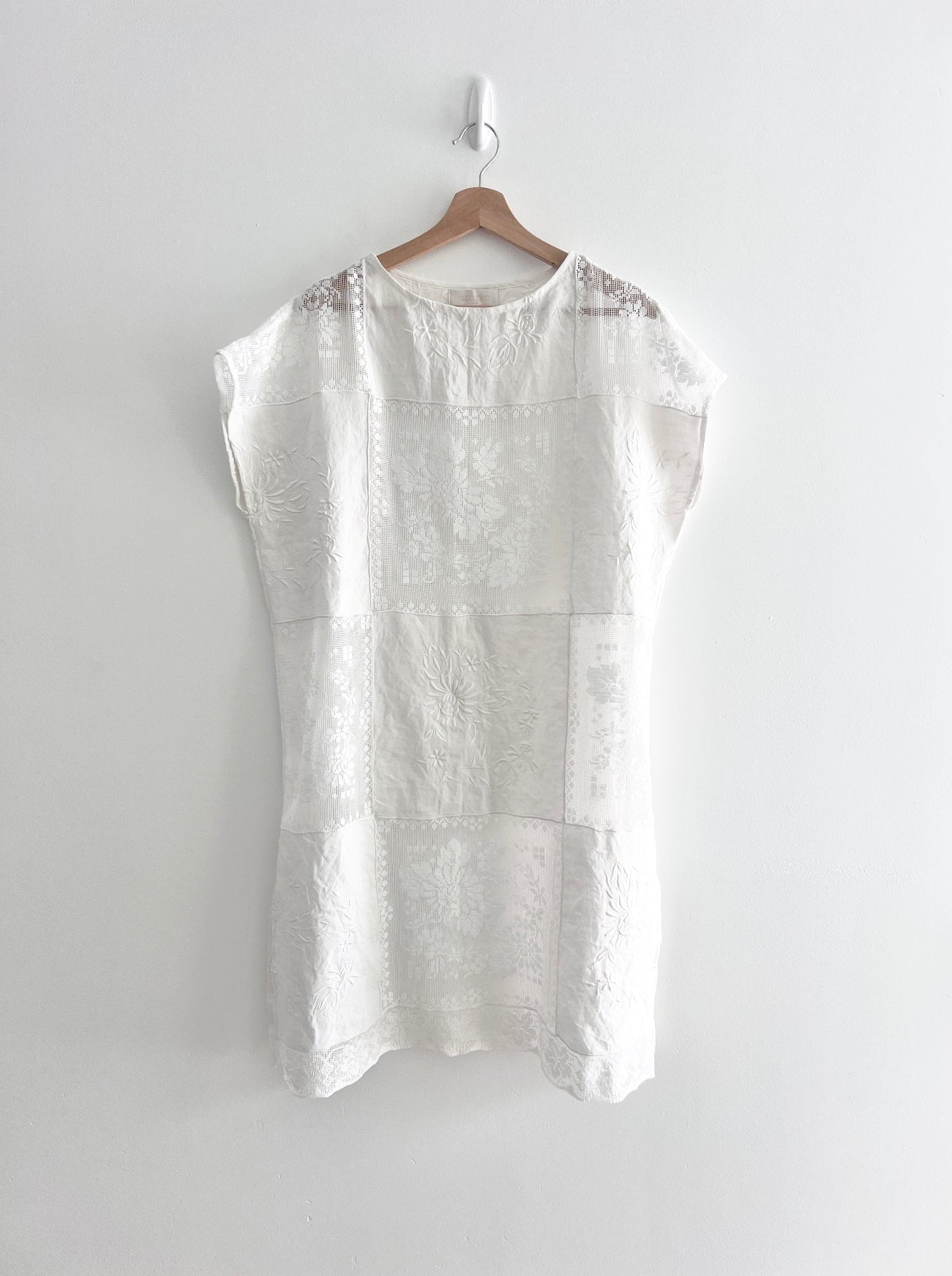 White sleeveless top on a hanger against a white background