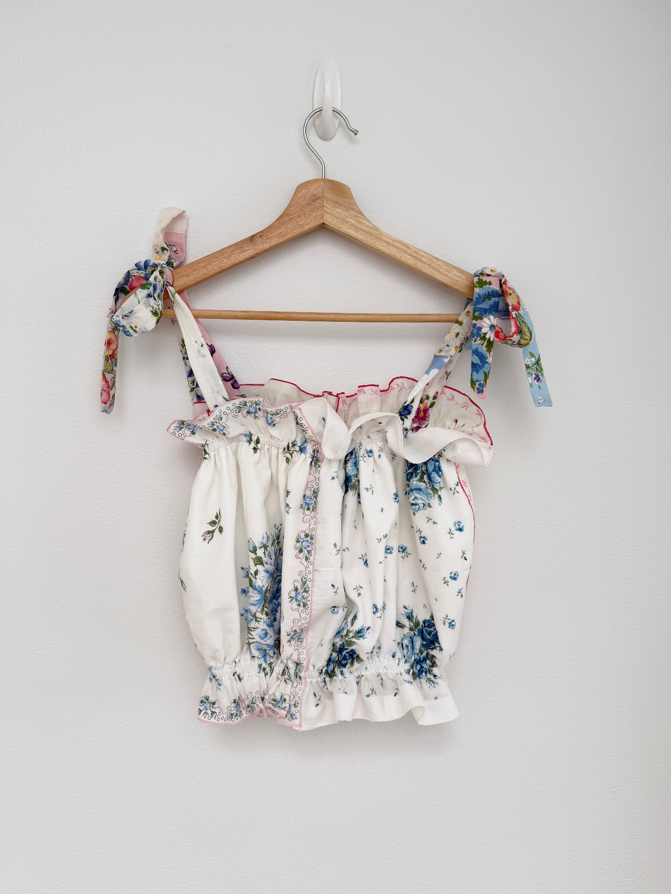 Floral top on a wooden hanger against a white background