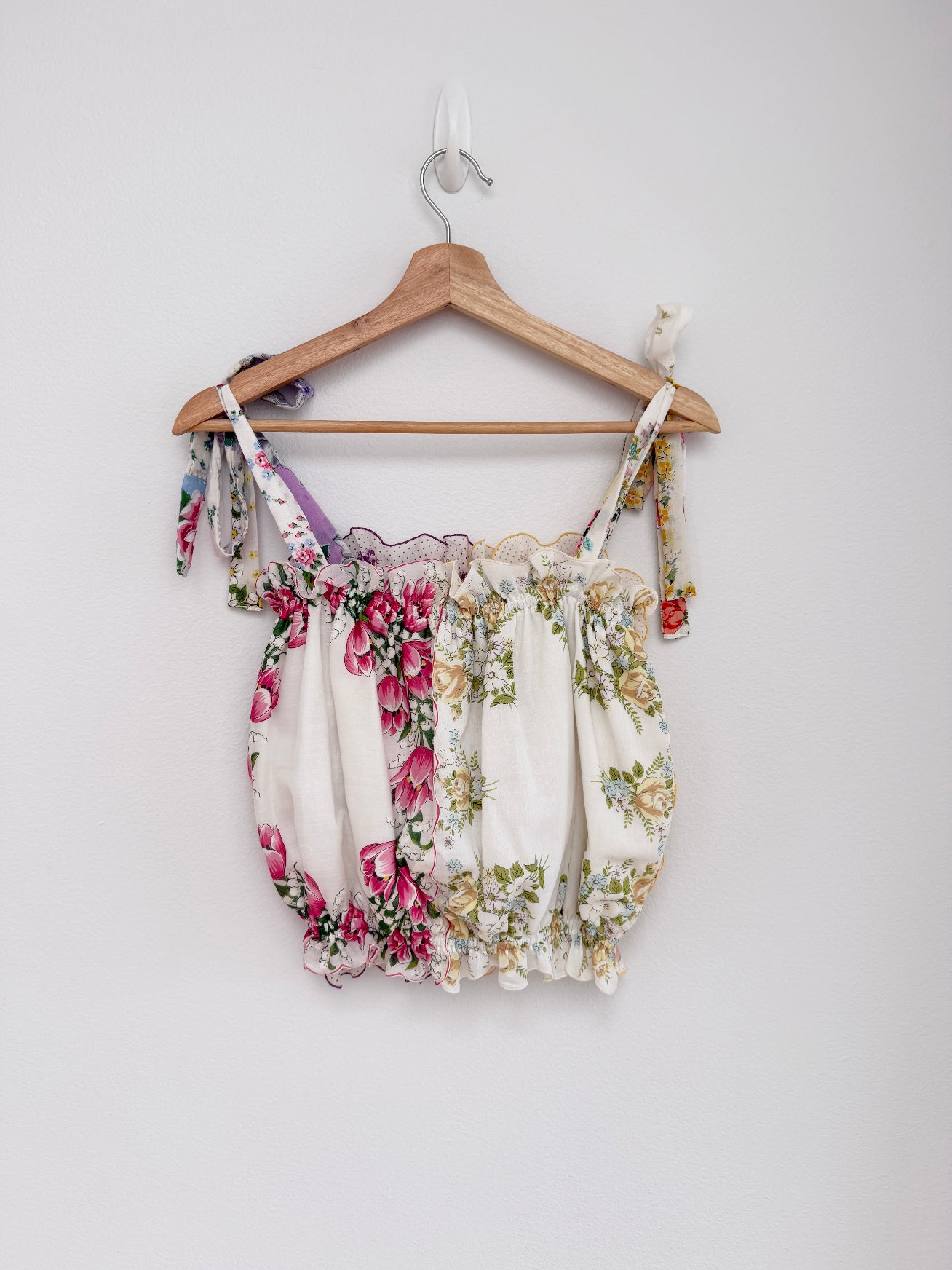 Floral top on a wooden hanger against a white background