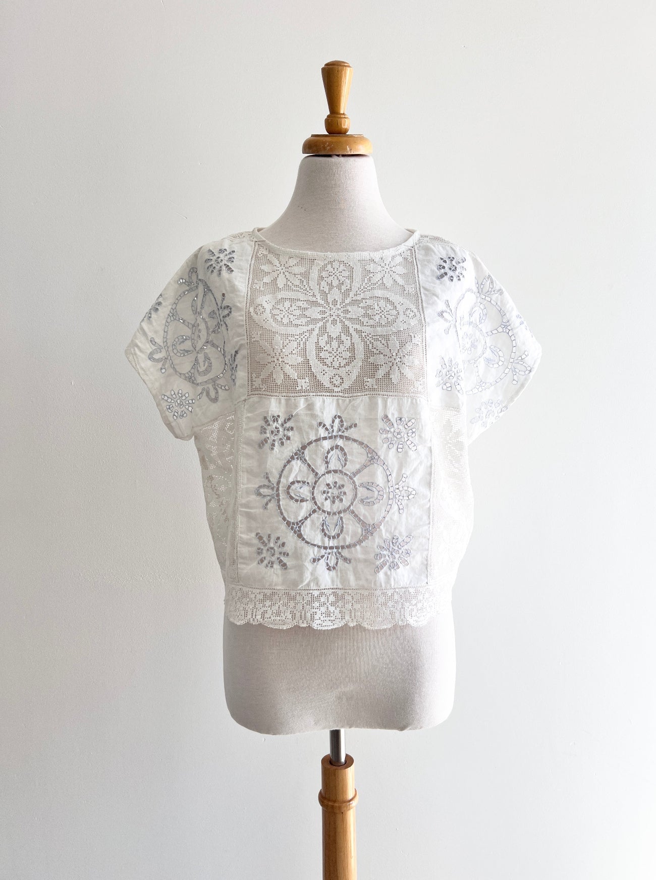White lace top on a mannequin against a plain background