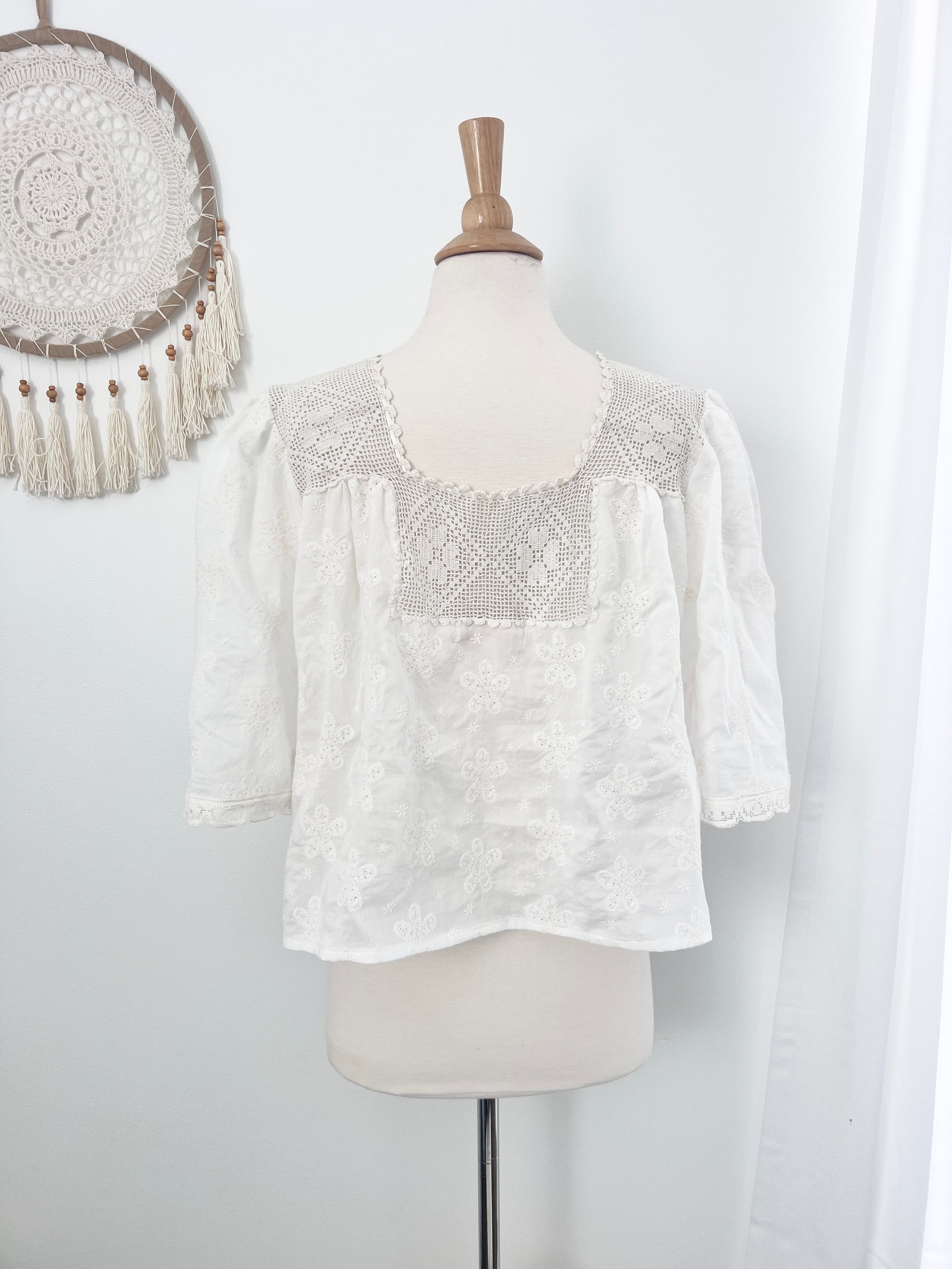 White lace top on a mannequin against a white background