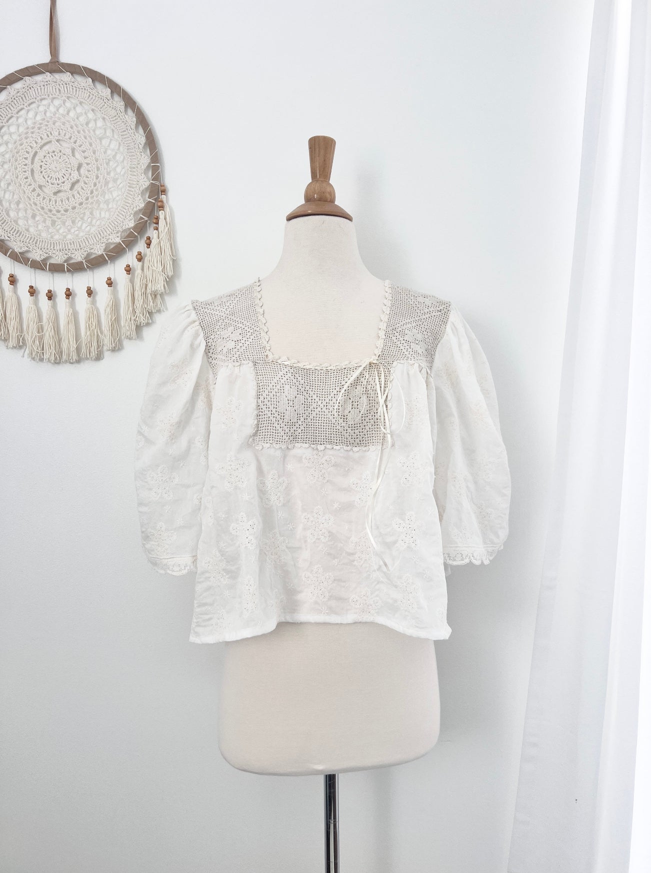 White blouse with lace detailing on a mannequin against a white background