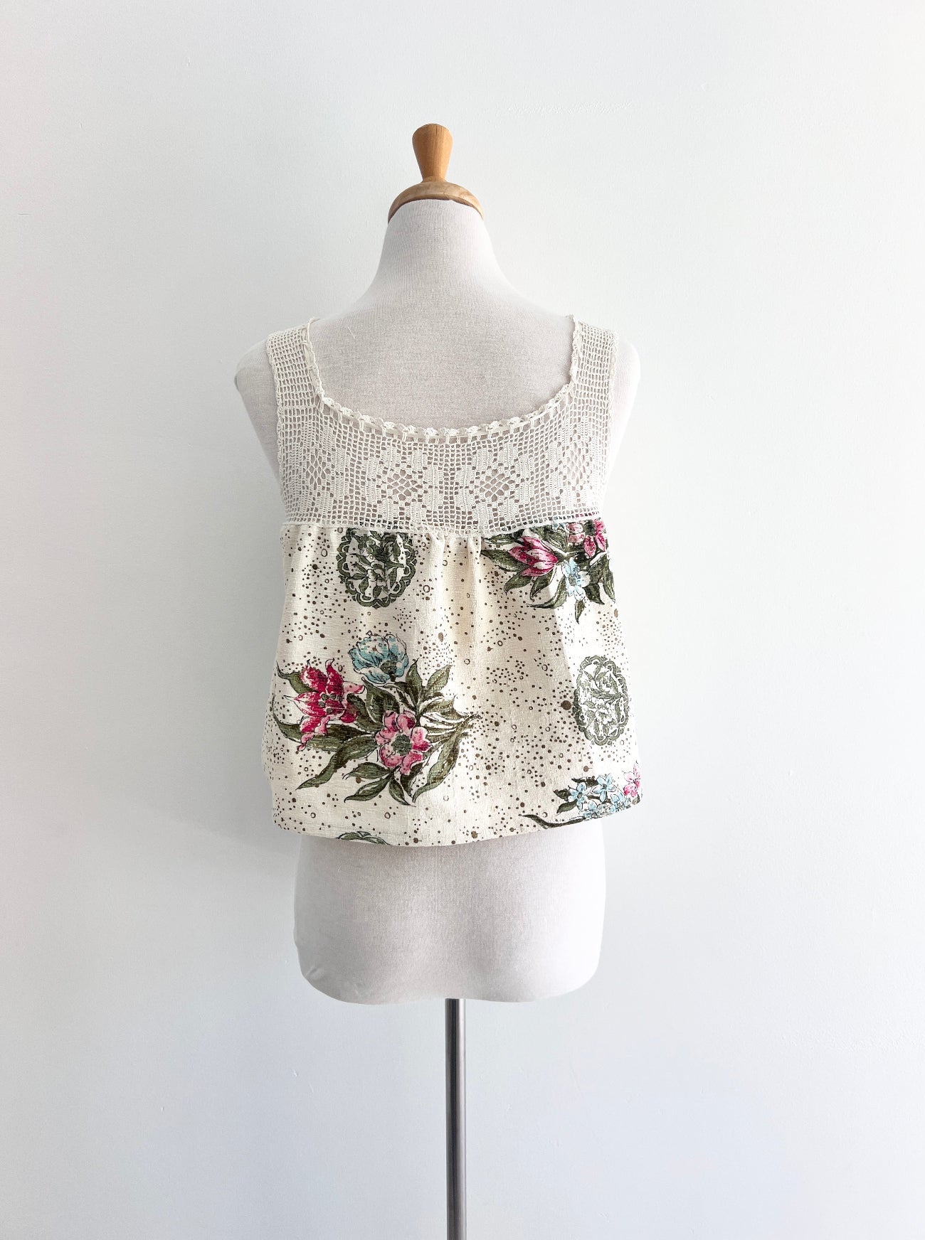 Floral tank top with lace details on a mannequin against a white background