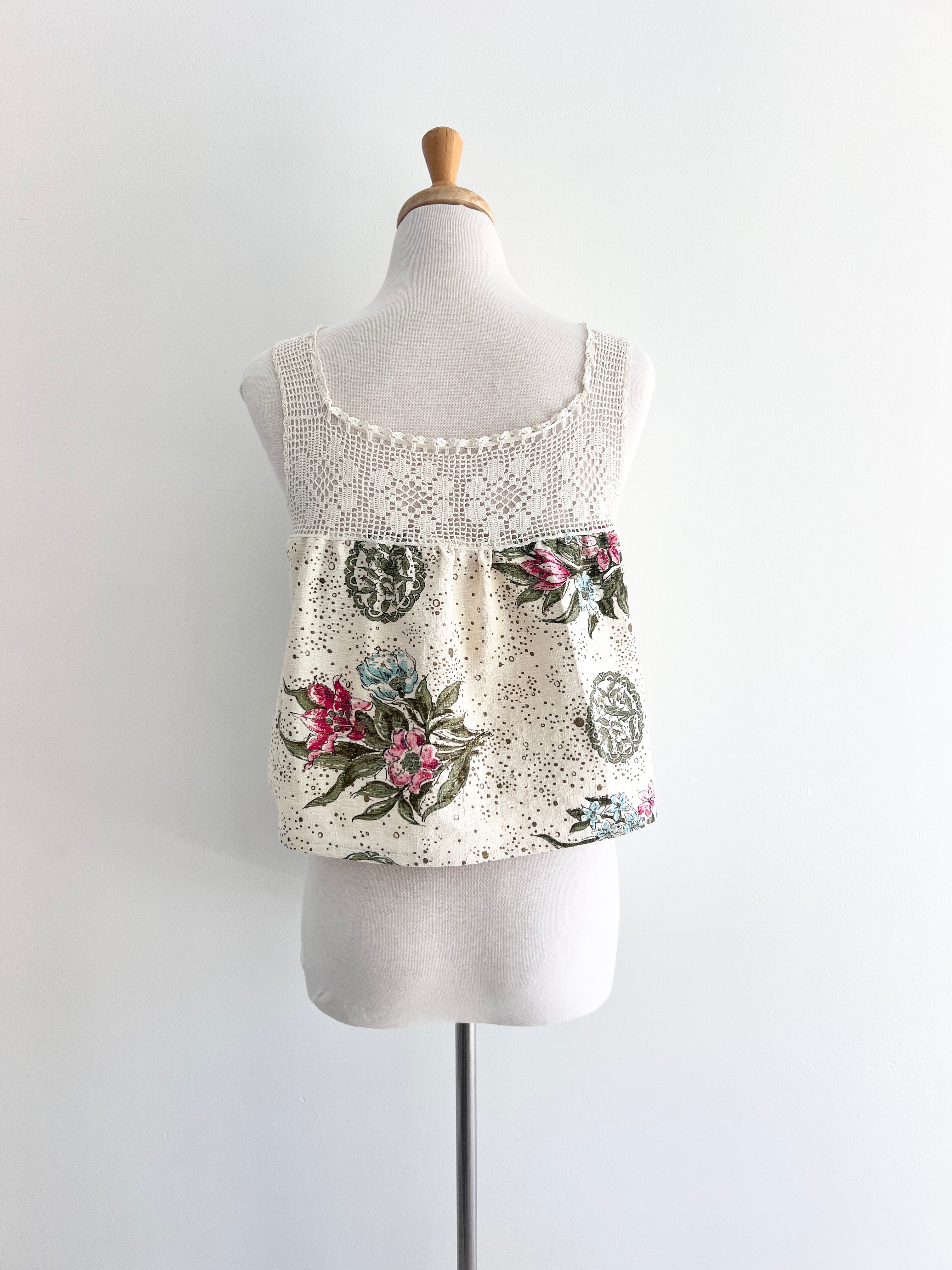 Floral tank top with lace details on a mannequin against a white background