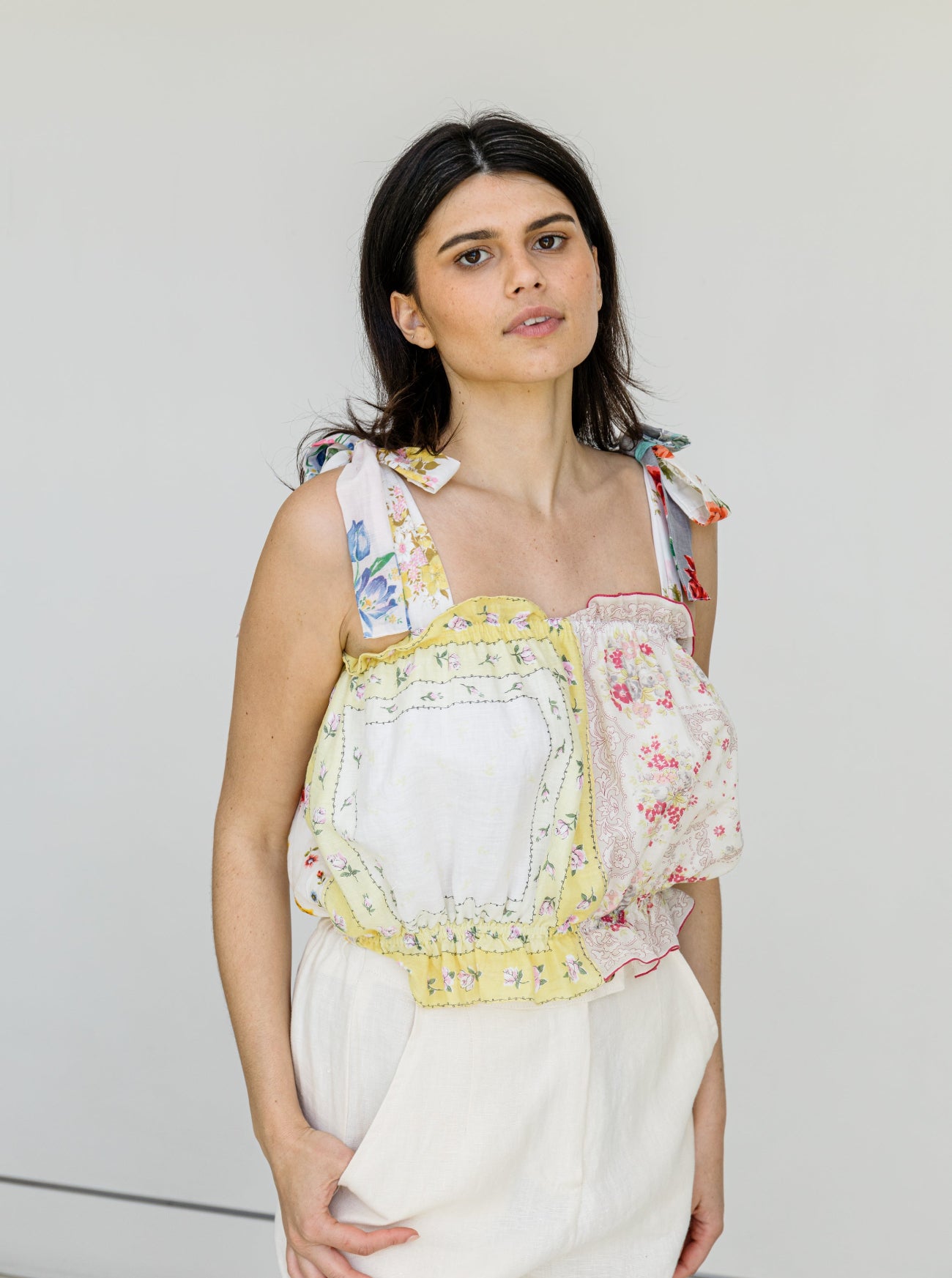 Woman wearing a colorful floral dress against a plain background