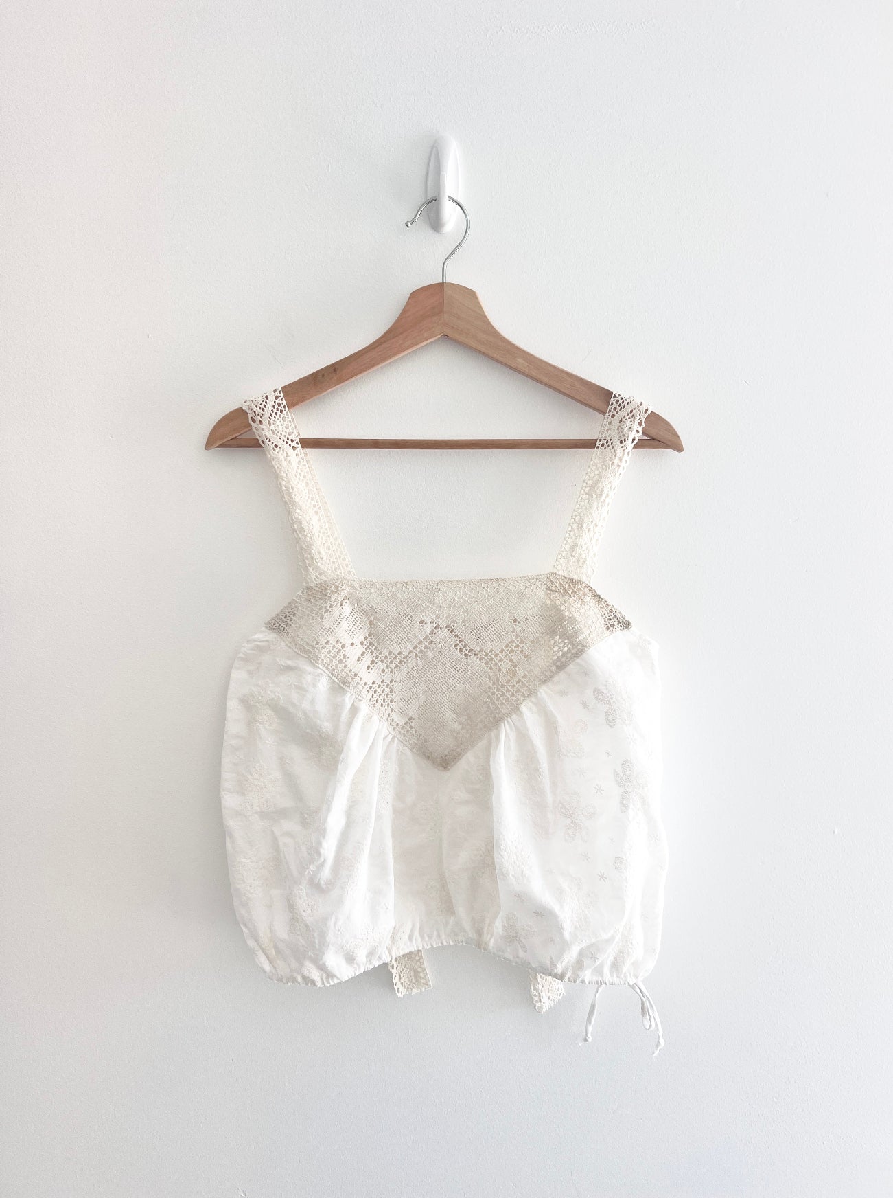 White lace top and shorts set on a wooden hanger against a white background