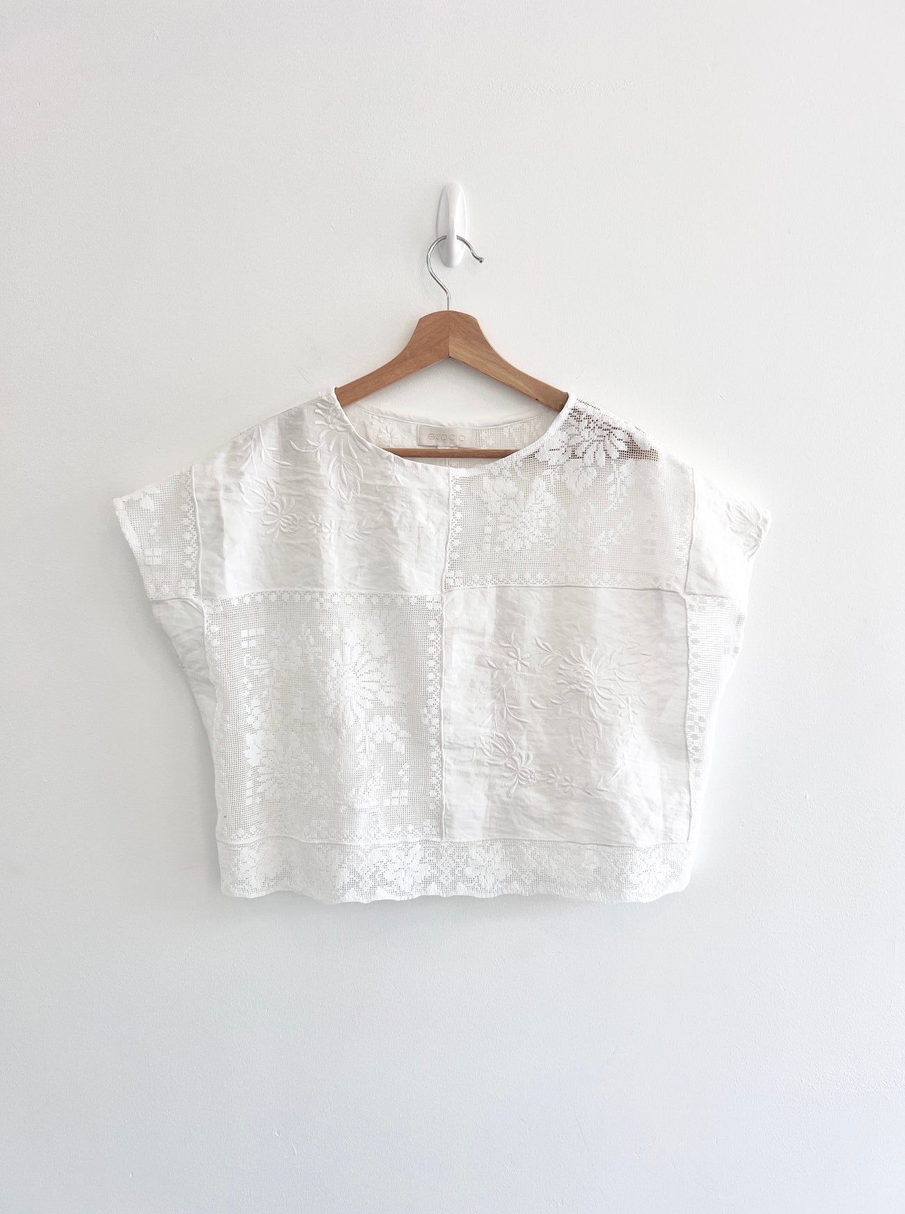White blouse on a wooden hanger against a white background