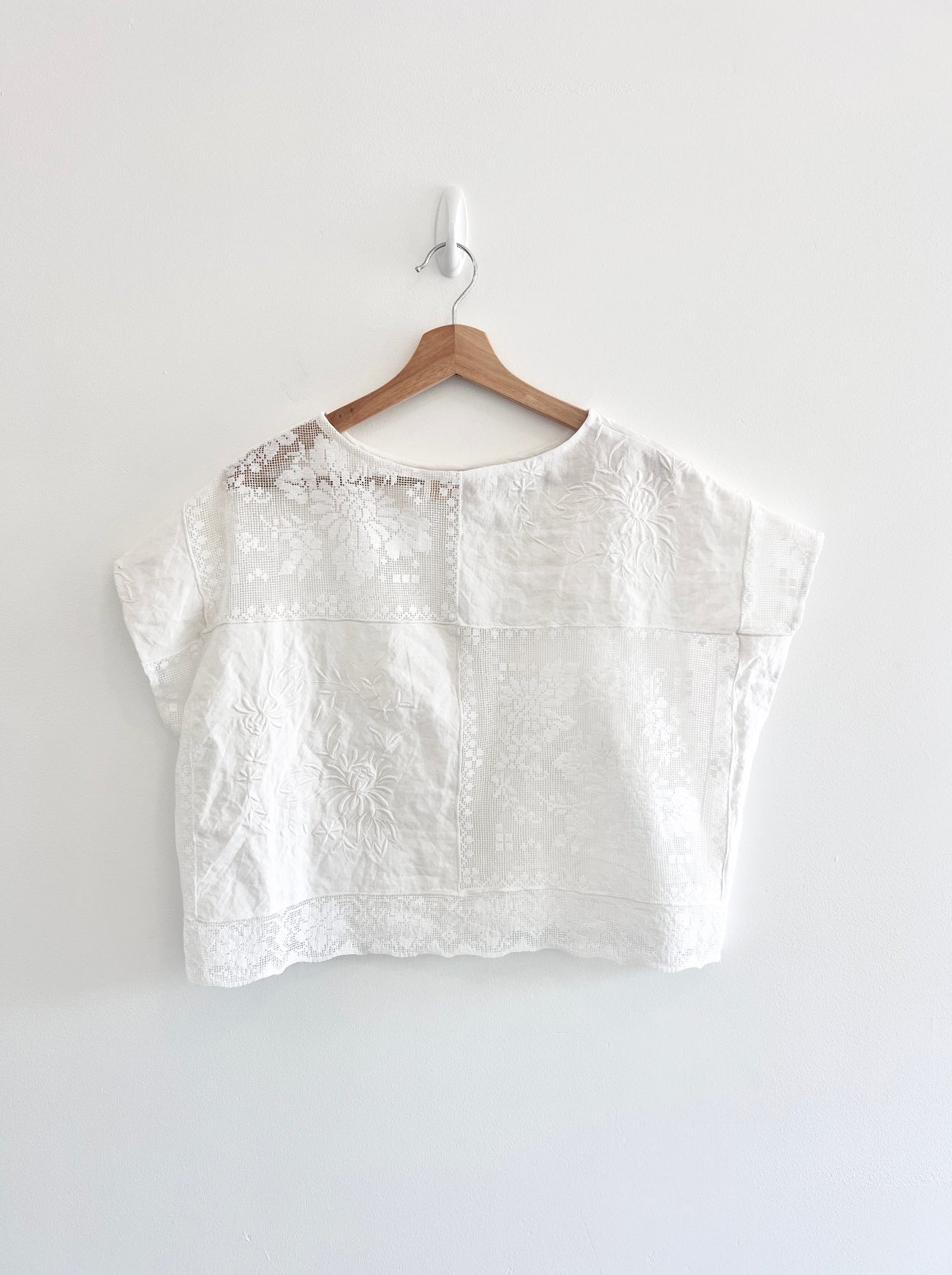 White blouse on a wooden hanger against a white background