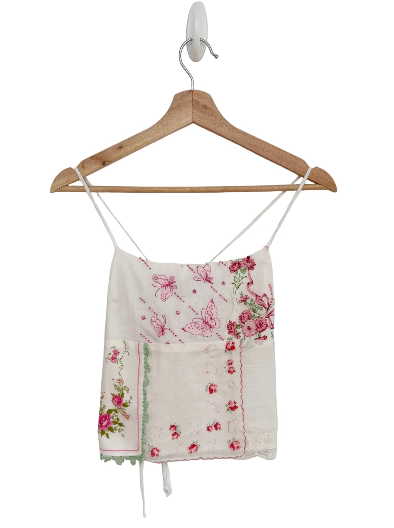 Floral embroidered top on a wooden hanger against a plain background
