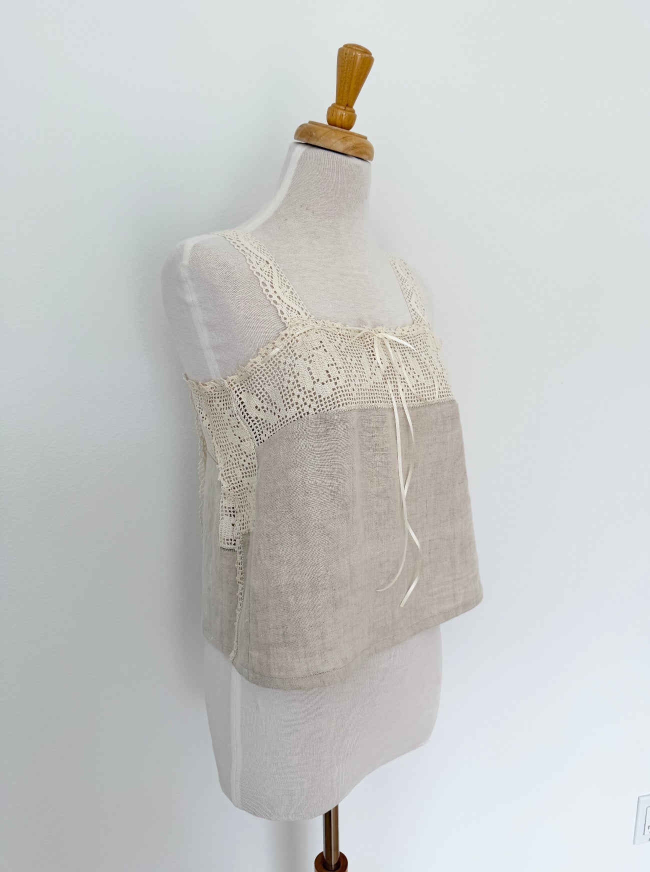 Lace-trimmed beige top on a mannequin against a white background