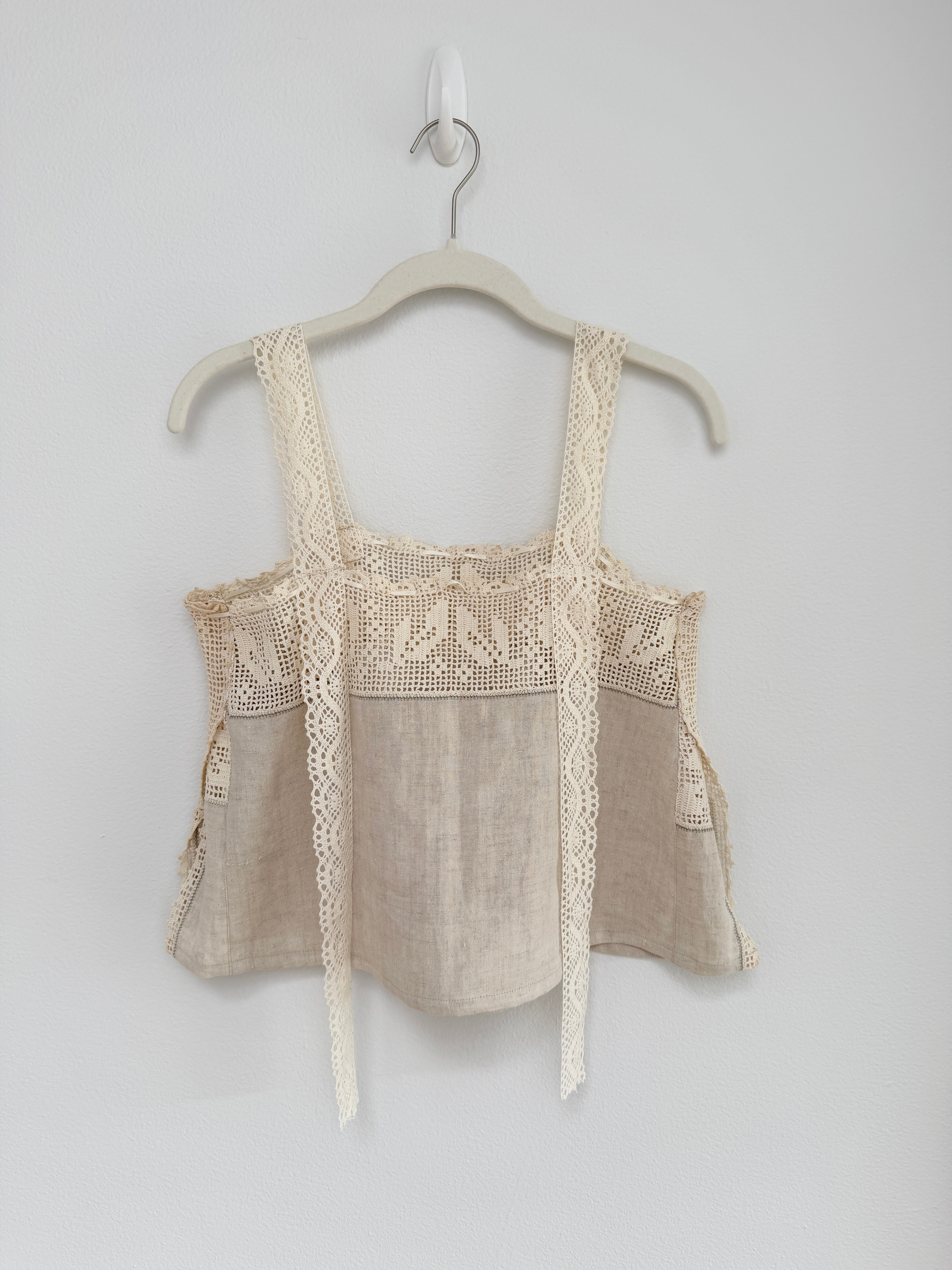 Beige lace top on a hanger against a white background