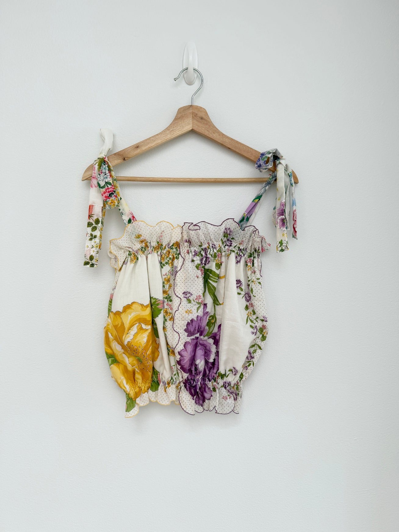 Floral-patterned top on a wooden hanger against a white background