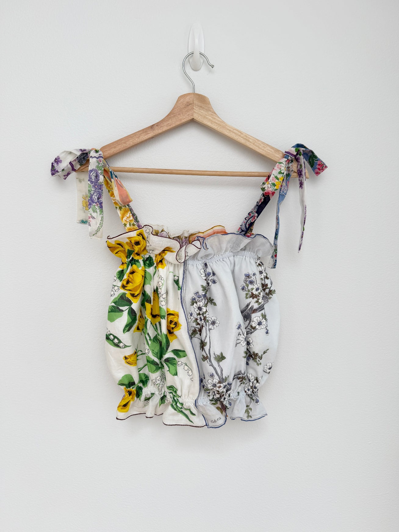 Floral-patterned top on a wooden hanger against a white background